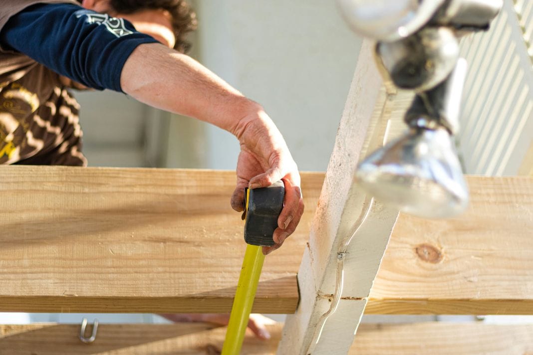 Builder measuring wood panel