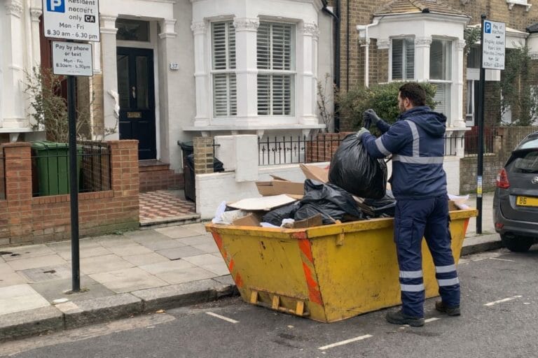 an illustrative image of waste being loaded into a small skip outside a London terraced house